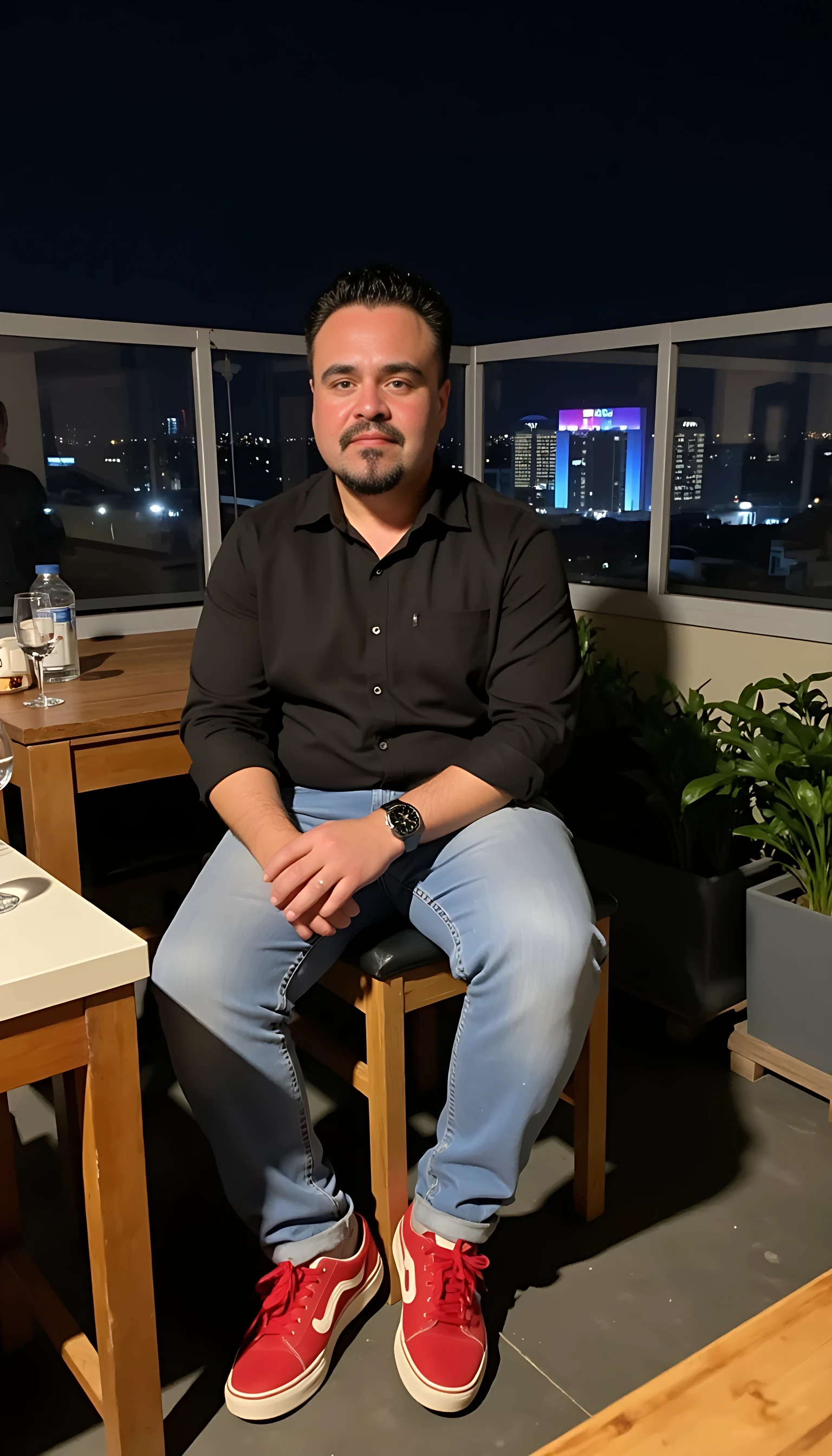  CSTMDL Man body wearing light blue jeans and black dress shirt red tenis shoes wearing a rolex watch seating on a nice restaurant  with a glass of wine on a rooftop city night lights  clear background 