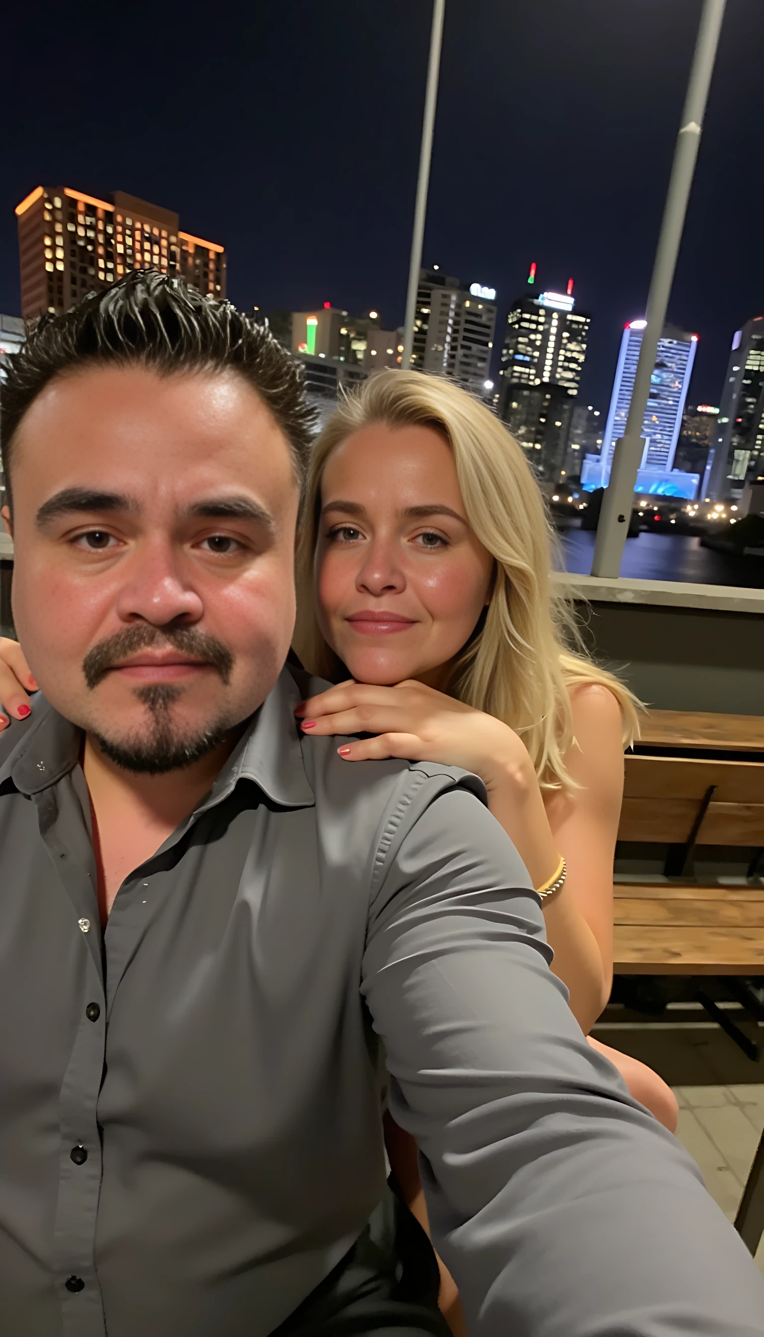 Selfie in a  mirror full man body wearing a  nice gray dress shirt   Hugging a beautiful blonde woman with blue eyes girl in a  big city night lights background 
