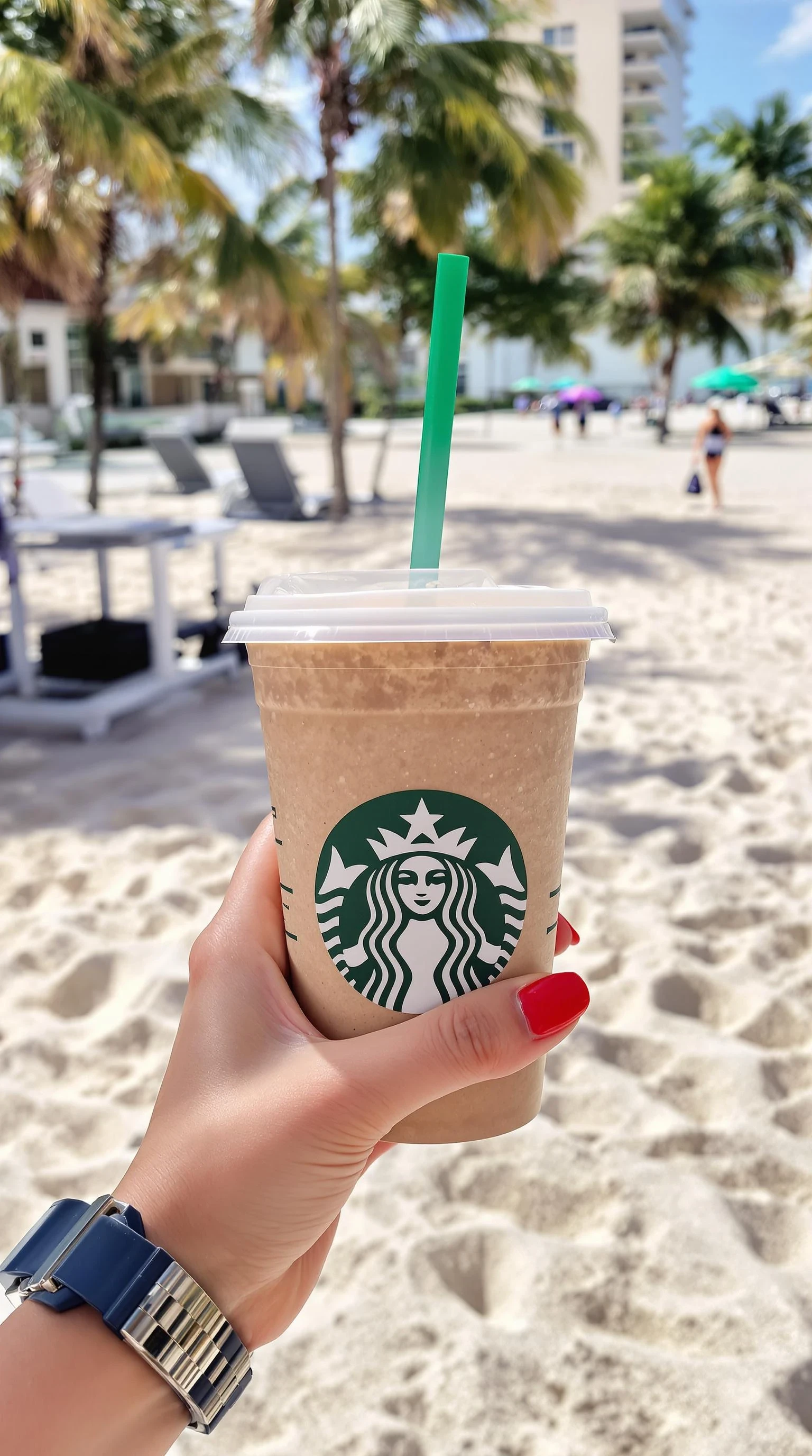 girl's hand holding starbuck coffee, red polished nails, at beach in miami