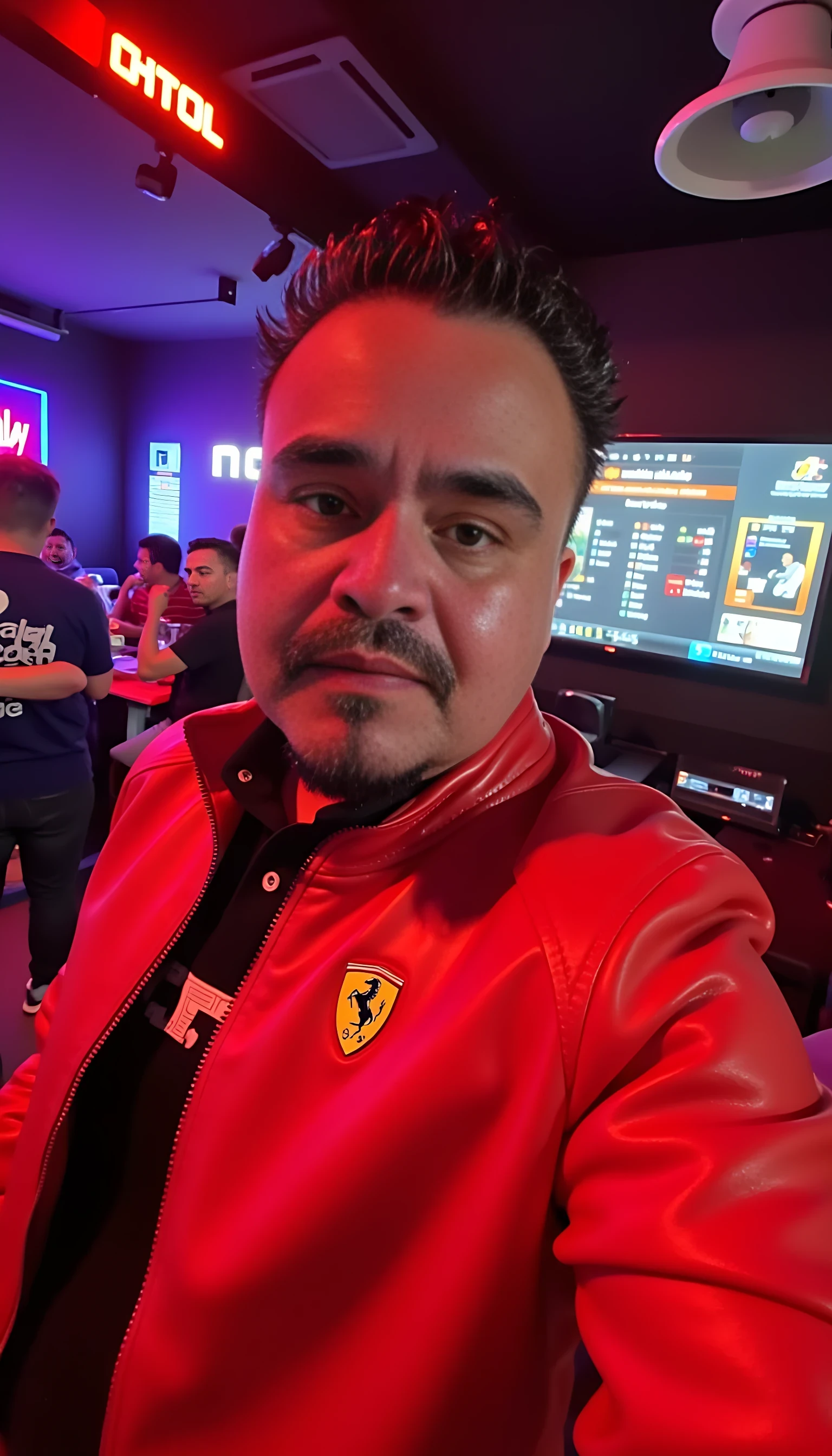 CSTMDL  selfie man average body wearing red leather jacket with a Ferrari logo standing 
With nightclub background 
