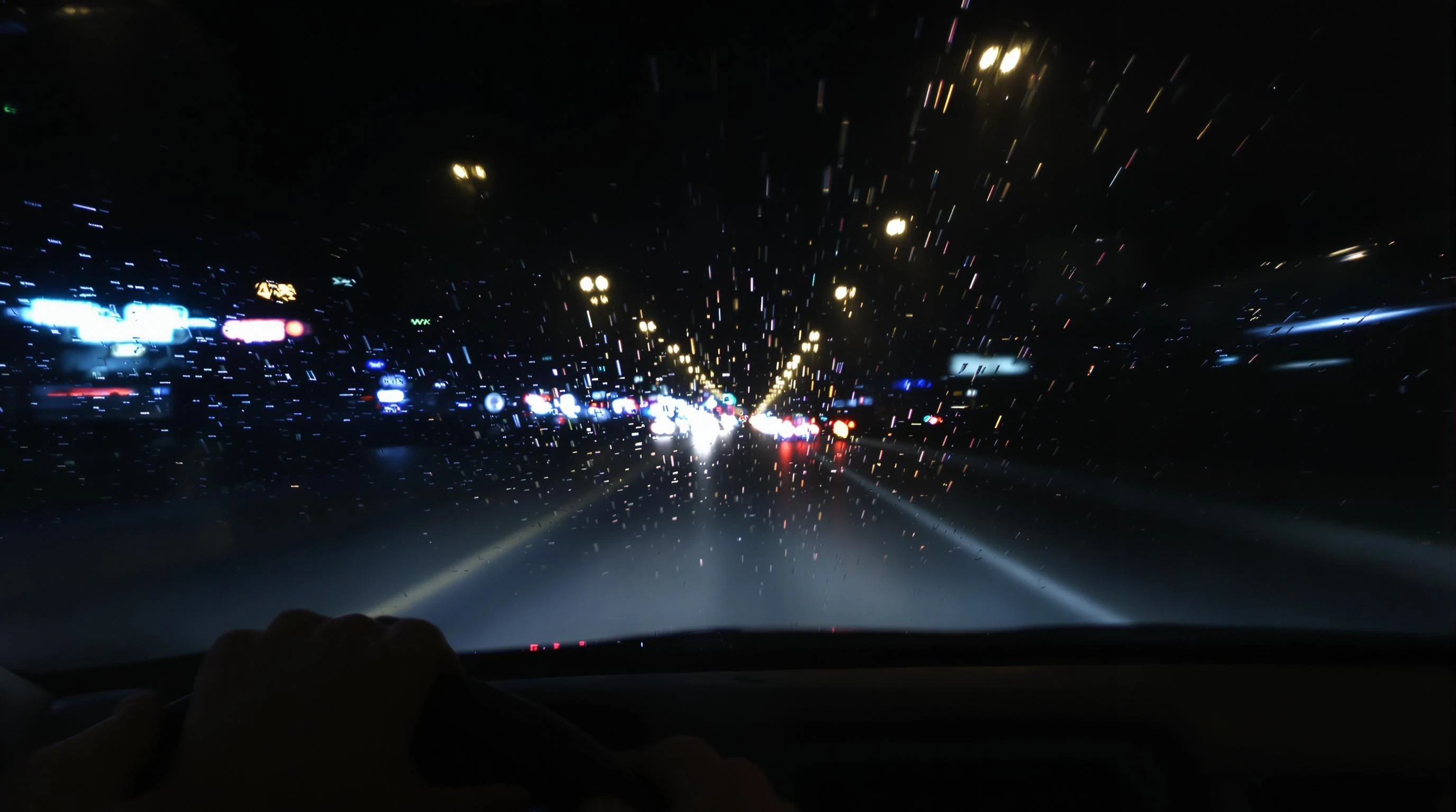 "A realistic nighttime scene viewed from inside a moving car, showing blurred city lights through a rain-covered windshield. The road is illuminated by soft neon reflections and distant headlights. The dashboard is visible in the foreground, with a pair of hands on the steering wheel, suggesting calm and focus. The mood is cinematic, introspective, and peaceful – ideal for a night drive. Ultra-realistic, moody lighting, 4K photo quality, shallow depth of field."