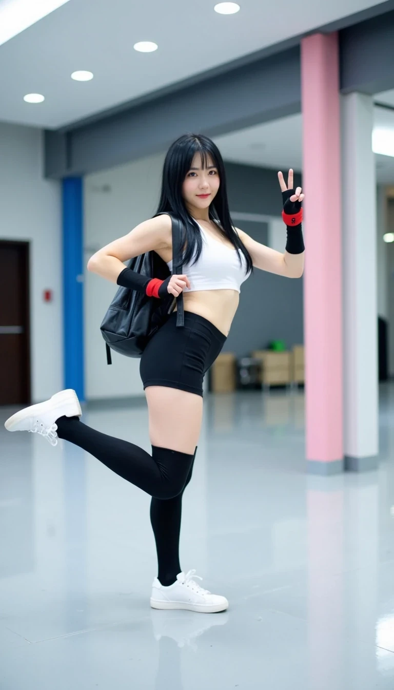 This photograph captures a young woman performing a high kick in a modern, well-lit indoor space, possibly a gym or convention hall. She has long, straight black hair with bangs, and is wearing a cosplay outfit inspired by Final Fantasy VII's character, Tifa Lockhart. The costume includes a white sports bra, black shorts, black thigh-high socks, and white sneakers. Her outfit is accessorized with black fingerless gloves and red wristbands, and she carries a black backpack slung over her shoulders.

Her skin is fair, and she has a slender, toned physique with large breasts. She is smiling and making a peace sign with her right hand, adding a playful and energetic vibe to her pose. Her left leg is extended high, showcasing her flexibility and agility.

The background features a clean, modern interior with a high ceiling and recessed lighting, providing a bright, even illumination. There are two large cylindrical pillars, one in blue and the other in pink, which likely serve as support structures or decor. The floor is a polished, light gray surface that reflects the surroundings. The overall ambiance is modern and sleek, emphasizing the clean lines and bright, open space.
